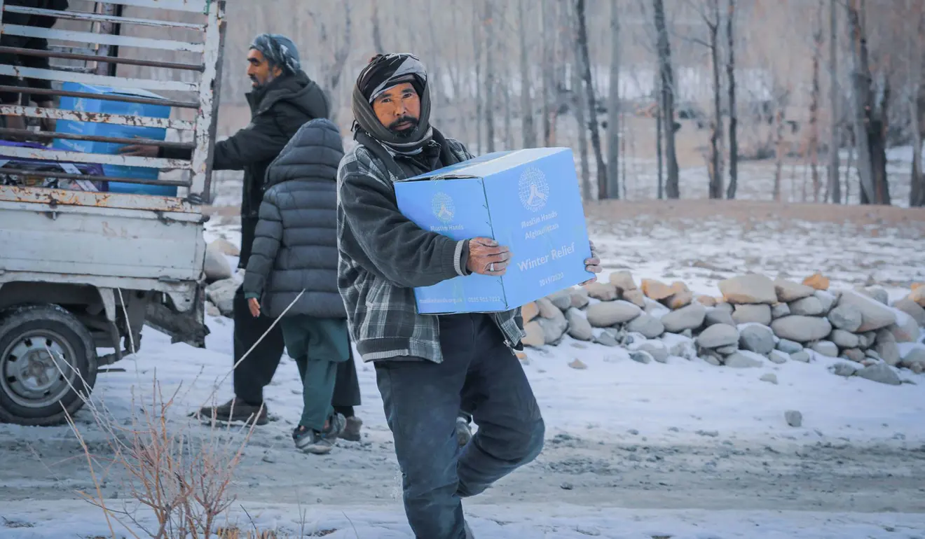 Man carrying a box of winter aid, smiling.
