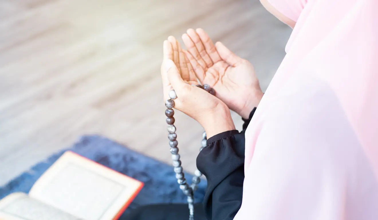 A woman makes du'a with a tasbeeh in her hands