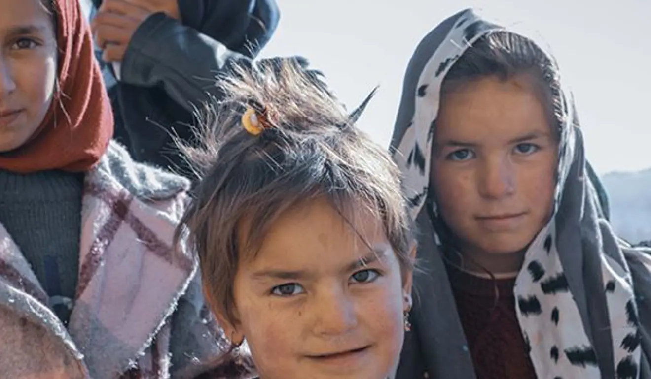 Children huddled in a group, cold and in layers.
