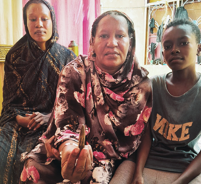 Syeda and her daughters sit together looking at the camera and holding a bullet