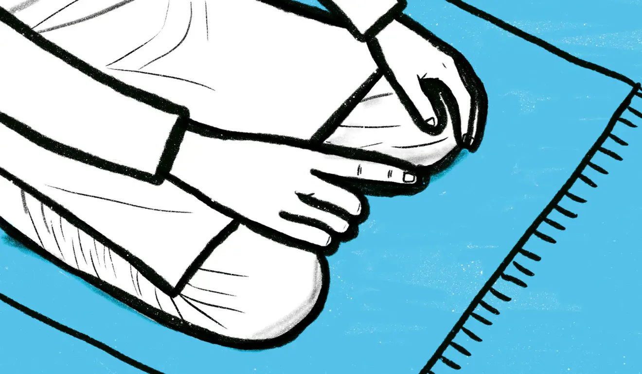 Zoomed up image of a man's palms resting on his knees with his right index finger pointing up.