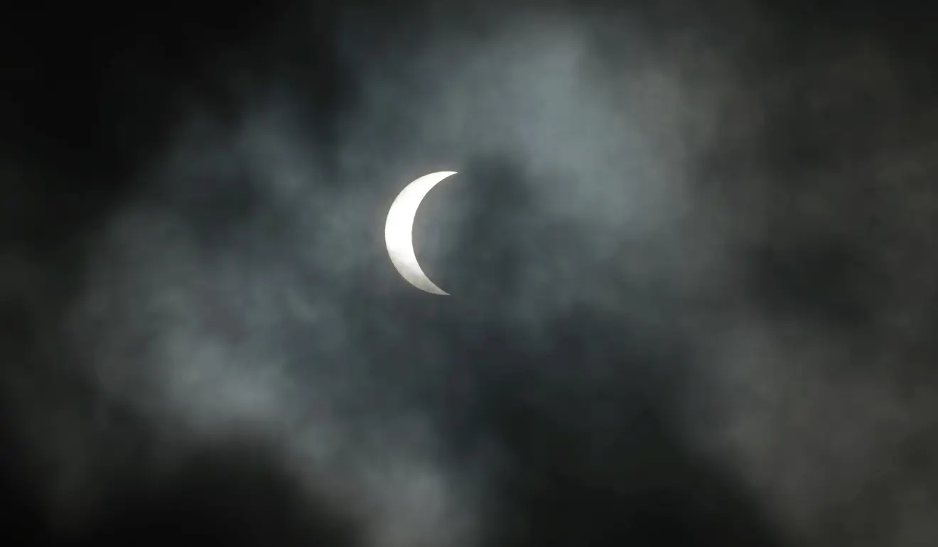 A solar eclipse sits amidst clouds. Image credit:NASA
